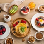 Un desayuno sin gluten con panqueques dorados, frutas frescas como fresas, arándanos y kiwi, aguacate, frutos secos, yogur y avena en un estilo saludable y nutritivo servido sobre una mesa de madera.